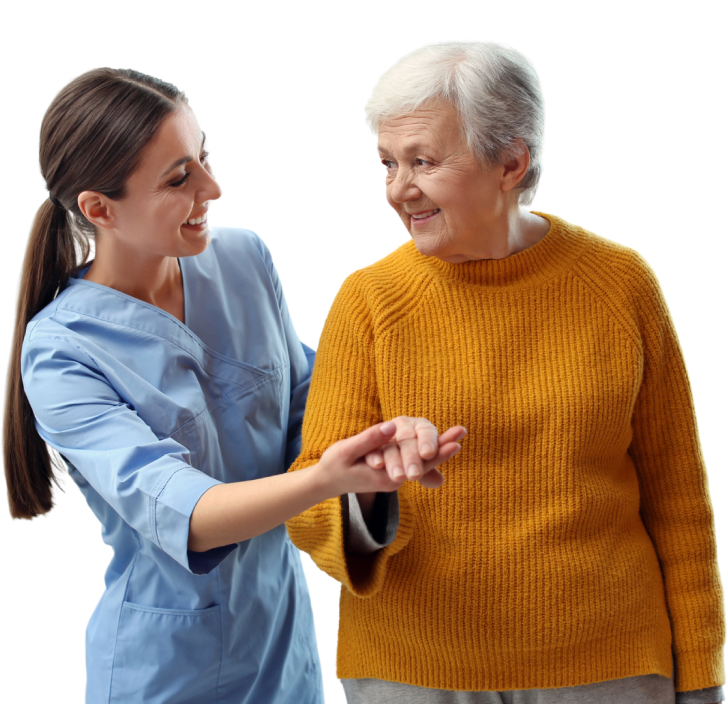 A caregiver in a blue uniform assists an elderly woman in a mustard sweater. Both are smiling and holding hands.